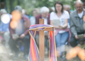 Kreuz beim Freiluftgottesdienst mit einem bunten Tuch geschmückt